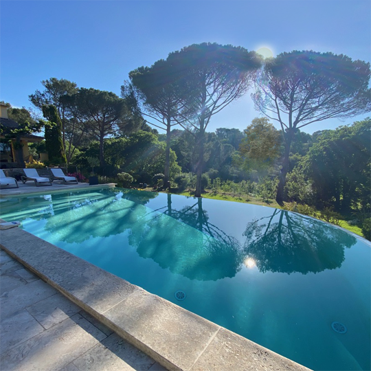 Infinity pool with pin parasols and sun behind